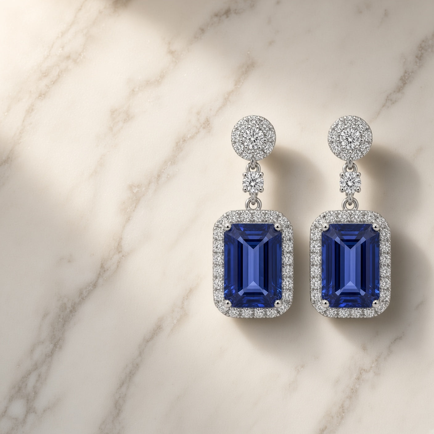 Tanzanite and diamond drop earrings in 18K white gold laid flat on white marble
