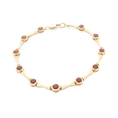 Isaac Westman garnet gold bracelet with red garnet stones and yellow 14K gold links, close-up view of elegant jewelry design.